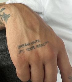 a man with a tattoo on his left hand and the words dream until it's your reality