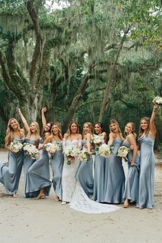 a group of women standing next to each other holding bouquets in front of trees