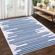 a blue and white area rug on the floor in front of a window with potted plants