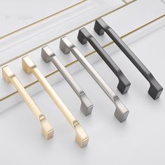 four different styles of handles and pulls on a white surface with gold trimmings