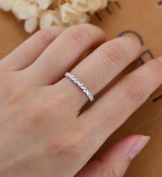 a woman's hand with a wedding ring on it and flowers in the background