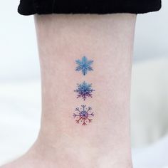 a snowflake tattoo on the ankle that is red, white and blue in color