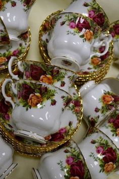 a table topped with lots of white and gold dishes covered in floral designs on them