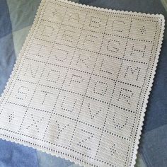 a white crocheted placemat sitting on top of a blue and white blanket