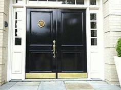 a black door with gold trim and two sidelights