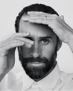 a black and white photo of a man holding his hands to his forehead