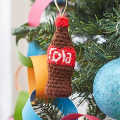 a crocheted ornament hanging from a christmas tree with decorations around it