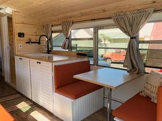 the interior of a mobile home kitchen and dining area with red cushions on the bench