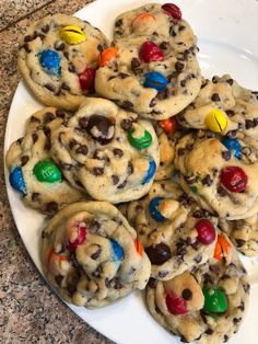 chocolate chip cookies with m & m candy on top are sitting on a white plate