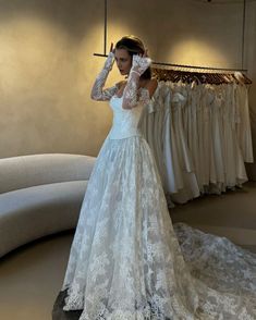 a woman in a white wedding dress standing next to a rack with dresses on it