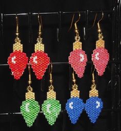 six different colored heart shaped beaded earrings hanging from hooks on a black rack in a store