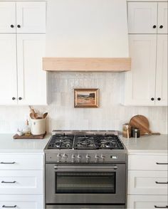 a stove top oven sitting inside of a kitchen next to white cupboards and drawers