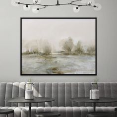 a painting hanging on the wall above a couch in a room with chairs and tables