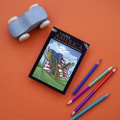 a skateboard, pencils and an american flag coloring book are on the table