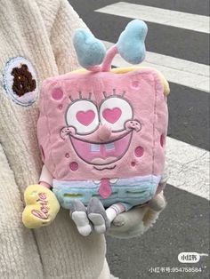 a person holding a pink spongebob backpack with hearts on it's chest