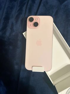 an iphone case sitting on top of a white box next to a blue cloth covered bed