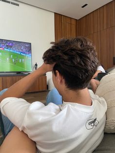 a young man sitting on the couch watching tv