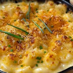 a casserole dish with cheese and chives in a black pan on a wooden table