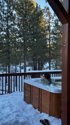 a hot tub with snow on the ground and trees in the background