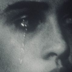 a black and white photo of a woman's face with tears on her eyes