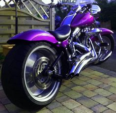 a purple motorcycle parked on top of a brick sidewalk