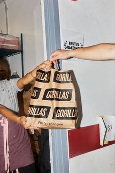 two people holding up a bag that says gorilla as it sits on top of another person's hand