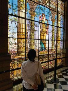 a woman standing in front of a stained glass window