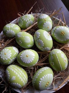 green and white decorated eggs sitting on top of straw