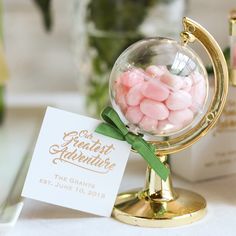 there is a small globe with candy in it and a card on the table next to it