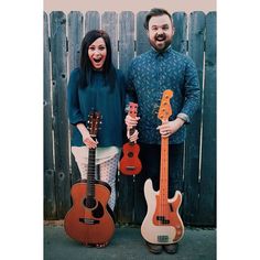 two people standing next to each other holding guitars