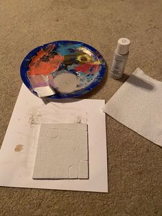 the paint is being used to make an art project on the floor with paper and glue