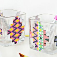 two clear cups filled with colored pencils on top of a white table next to each other