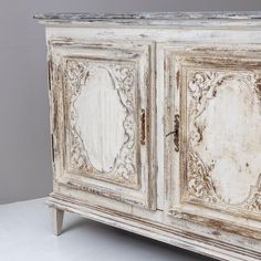 an old white cabinet with ornate carvings on the doors