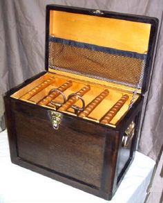 an open wooden box with two wedding rings in it on a white cloth covered table