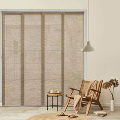 a living room with a chair, table and window blinds in shades of beige color