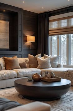 a living room filled with lots of furniture next to a window covered in brown and white pillows