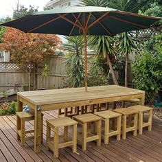 a wooden table and bench with an umbrella over it on a deck in the backyard