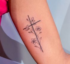 a cross and flowers tattoo on the right arm, with one flower in it's center