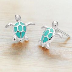 Dive into artistic elegance with our Enamel Sea Turtle Studs—a creative masterpiece crafted to transport wearers to blissful, sun-filled days by the ocean. These earrings aren't just accessories; they are wearable art designed to embody the tranquil beauty of sea turtles gliding through the azure waves. Elevate your style effortlessly by pairing these unique studs with our exclusive collection of nautically-inspired pieces, creating a harmonious ensemble that mirrors the allure of maritime life. Handmade Ocean Color Jewelry For Summer, Handmade Ocean Color Summer Jewelry, Silver Earrings For Summer Vacation, Hypoallergenic Summer Vacation Jewelry, Ocean-inspired Green Jewelry For Vacation, Green Ocean-inspired Jewelry For Vacation, Ocean-inspired Jewelry For Summer Gifts, Ocean-inspired Jewelry For Summer, Summer Ocean-inspired Jewelry In Ocean Color