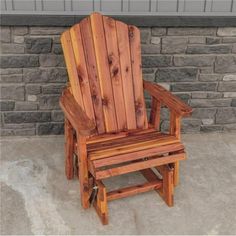 a wooden chair sitting in front of a brick wall on concrete floor next to a stone wall