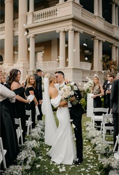 a bride and groom kiss as they walk down the aisle with confetti thrown in the air