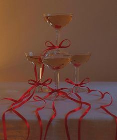 three martini glasses with red ribbons on a table