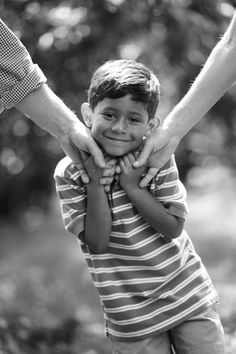 a black and white photo of a little boy holding his parents hands