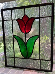 a stained glass window with a red flower in the center and green leaves on it