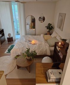 a bed room with a neatly made bed next to a window and a plant on the table