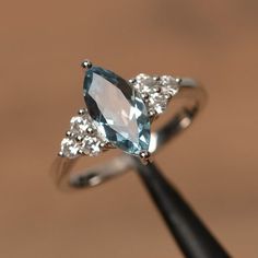 a blue and white diamond ring sitting on top of a wooden stick