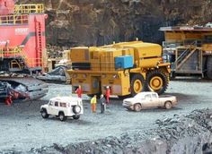 there are cars and trucks parked in front of a construction site with large rocks behind them