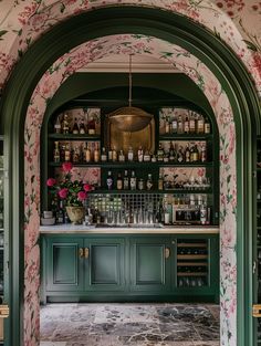 a bar with green cabinets and floral wallpaper