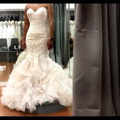 a woman standing in front of a mirror wearing a wedding dress with ruffles