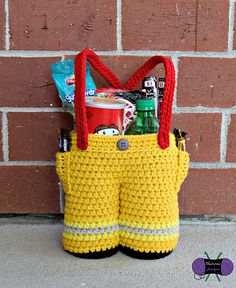 a crocheted yellow bag with red handles is sitting next to a brick wall